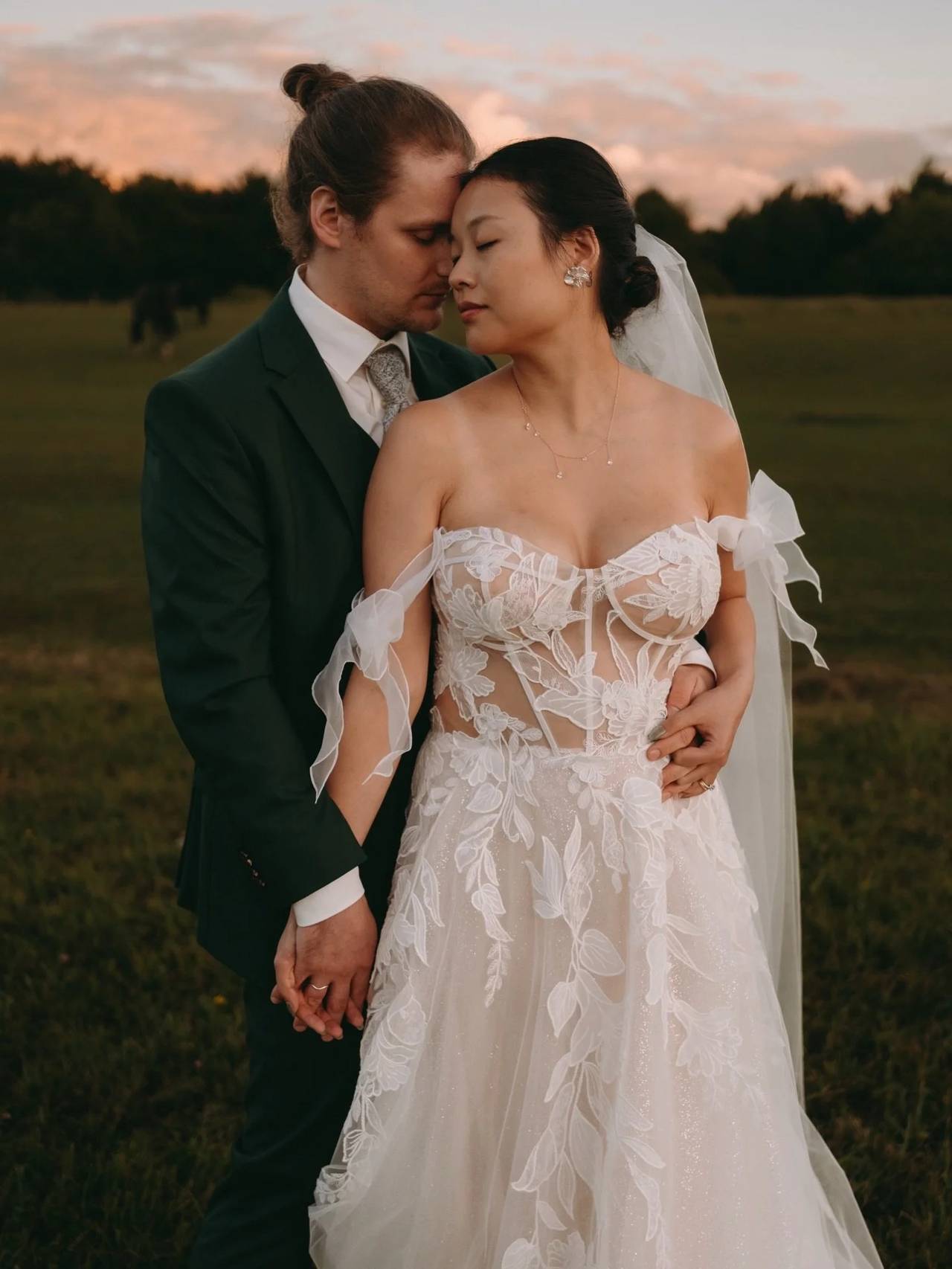 Brautpaar auf Wiese bei Sonnenuntergang, Braut im Spitzenkleid