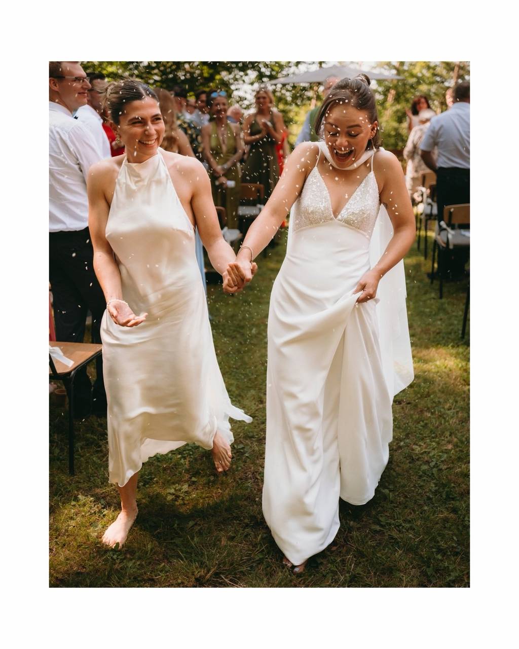 Gleichgeschlechtliches Brautpaar lacht beim Konfetti-Regen — authentische Hochzeitsreportage